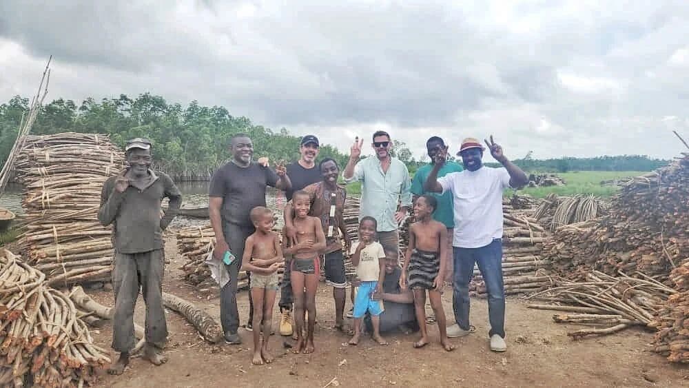 Community members beside stacks of felled mangrove wood