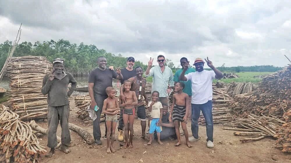 The team with community members beside stacks of felled mangrove wood